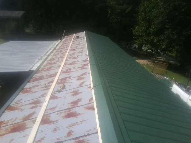 Old rusted panels beside newly installed green metal roofing — Wind Damage Roof Repair by Roofing Brothers in Stratford