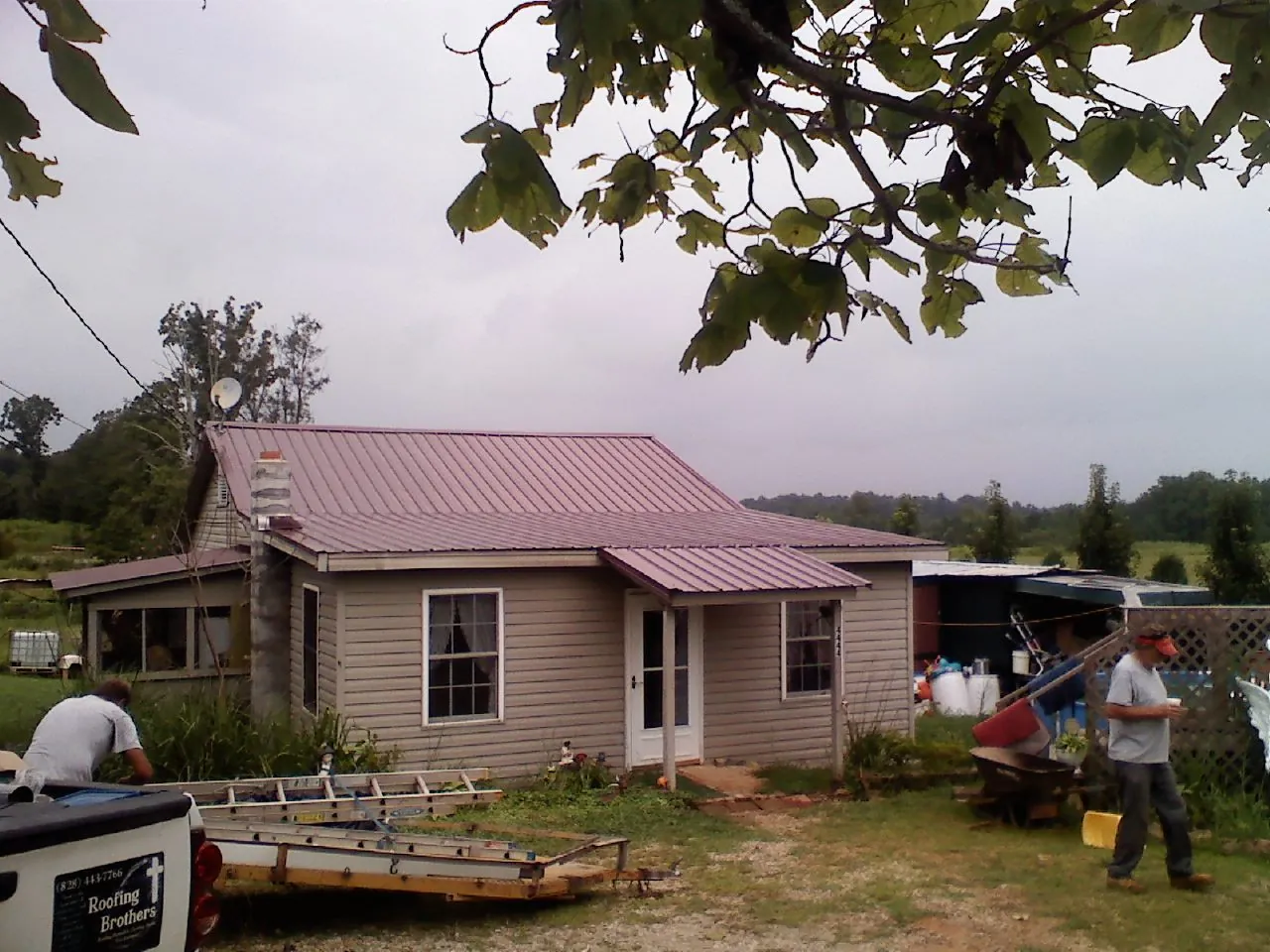 Crew finishing a mauve metal roof on a small farmhouse in Stratford